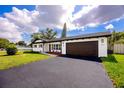 Charming single-story home with a dark roof and driveway, lush lawn, and beautiful landscaping at 1873 Murray Ave, Clearwater, FL 33755