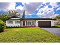 Well-manicured front yard featuring a white home with dark trim, and a lush lawn at 1873 Murray Ave, Clearwater, FL 33755