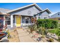 Charming home's front entrance with a bright yellow door and beautiful landscaping at 2611 San Luis Rd, Holiday, FL 34691