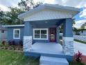 Inviting front porch of a blue house, complemented by stone accents and an attractive red door at 3718 N 36Th St, Tampa, FL 33610