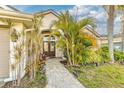 Close up of the front door and entrance way, lush landscaping, and a brick path walkway at 447 Bridle Path Way, Tarpon Springs, FL 34688