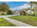 Inviting home boasts lush landscaping, mature palm trees, well-kept lawn, and spacious driveway at 447 Bridle Path Way, Tarpon Springs, FL 34688