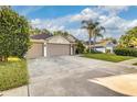 Attractive single-story home shows a well-maintained lawn, mature trees, and an expansive driveway at 447 Bridle Path Way, Tarpon Springs, FL 34688
