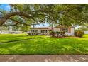Charming single-story home with vibrant landscaping, well-maintained lawn, and mature shade tree at 5800 3Rd S St, St Petersburg, FL 33705
