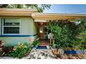 Cozy entrance with a covered porch adorned with plants, stone accents, and blue trim at 6618 N 11Th St, Tampa, FL 33604