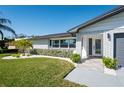 Close up of the attractive front exterior with a well kept lawn, white brick, and a modern front door at 14261 113Th Ave, Largo, FL 33774