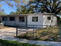 Exterior angle view of a white single-story home, showcasing the front yard with chain-link fence at 1716 Lancelot Loop, Tampa, FL 33619