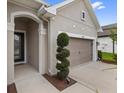 Close-up of the front entry and two-car garage, with a decorative shrub at 1767 Tonka Ter, Wesley Chapel, FL 33543
