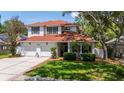 Charming two-story home boasts a red roof, a two-car garage, and a well-manicured lawn surrounded by mature trees at 2015 Long Branch Ln, Clearwater, FL 33760