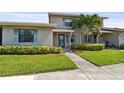 Home exterior with blue shutters, lush green lawn, and mature tropical trees in the front of the property at 2131 Ridge S Rd # 3, Largo, FL 33778