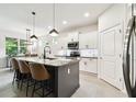 Modern kitchen with gray island, granite countertops, pendant lighting, and stainless appliances at 32825 Sand Creek Dr, Wesley Chapel, FL 33543