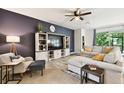 Spacious living room features an entertainment center, comfortable seating, ceiling fan, and neutral-toned tile flooring at 32825 Sand Creek Dr, Wesley Chapel, FL 33543