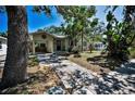 Charming home with mature trees, a carport, and a stone walkway leading to the inviting front entrance at 420 Roanoke St, Dunedin, FL 34698