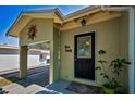 Inviting front door with decorative glass, a small porch, and a carport adorned with a sun decoration at 420 Roanoke St, Dunedin, FL 34698