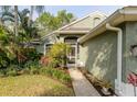 Charming home exterior with lush landscaping, including tropical plants near the front door at 5619 Essex Ct, Palm Harbor, FL 34685