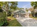 Inviting single-story home with a three-car garage, manicured lawn, and mature landscaping at 5619 Essex Ct, Palm Harbor, FL 34685
