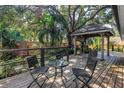 Outdoor living space featuring a spacious wooden deck with gazebo, seating and lush foliage at 7461 Pescador Pl, Seminole, FL 33772