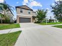 A two-story home featuring a long driveway leading to a gray garage door and landscaping at 9605 Channing Hill Dr, Sun City Center, FL 33573