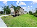 Exterior view of a well maintained house with a lush green lawn, a long driveway, and mature trees at 9605 Channing Hill Dr, Sun City Center, FL 33573