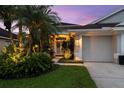 Home exterior featuring a lush green lawn, tropical plants, and an attached two-car garage at 10516 Gretna Green Dr, Tampa, FL 33626