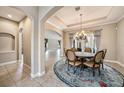 Open-concept dining room with tile floors, a decorative rug, and a chandelier creates an elegant dining space at 10645 Ruffino Ct, Trinity, FL 34655