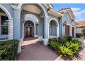 Arched entrance to a blue home, showcasing the brick walkway and manicured landscaping around the front door at 10645 Ruffino Ct, Trinity, FL 34655