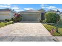 Inviting single-story home with a brick paved driveway and an American flag at 1110 Jasmine Creek Ct, Sun City Center, FL 33573