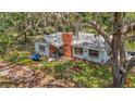 Cozy single-story home with a brick chimney, nestled amid mature trees, providing natural shade at 11912 Mcmullen Loop, Riverview, FL 33569