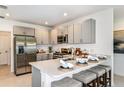 Modern kitchen with stainless steel appliances, gray cabinetry, quartz countertops, and breakfast bar seating at 12435 Gust Ct, Hudson, FL 34669