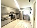 Bright kitchen with stainless steel appliances, grey cabinets, tiled backsplash, and neutral tile flooring at 13100 Serpentine Dr, Hudson, FL 34667