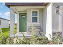 Cozy front porch with a green door, complemented by a small bench and lush landscaping at 13958 Richland Gulf Cir, Parrish, FL 34219