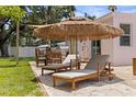 Relaxing backyard with lounge chairs under a thatched umbrella, with an outdoor dining area nearby at 1579 Bayshore Blvd, Dunedin, FL 34698