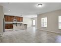 Open-concept living room with tile floors, plenty of natural light, and a kitchen with stainless steel appliances at 16016 Persimmon Grove Dr, Lithia, FL 33547