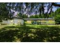 Charming single-story home with a well-manicured lawn, mature trees, and a welcoming blue front door at dusk at 2205 Henley Rd, Lutz, FL 33558