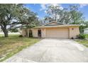 Single-story home with a front yard, driveway, attached garage, and arched gate at 2410 Covington Ave, Spring Hill, FL 34608