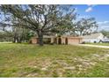 Charming single-story home with arched gate, front yard, and a large mature shade tree in a residential setting at 2410 Covington Ave, Spring Hill, FL 34608