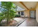Inviting covered front patio with tiled floor, garden area, and natural light at 2410 Covington Ave, Spring Hill, FL 34608