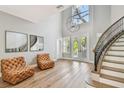 Bright foyer with two-story ceilings, light wood floors, tufted leather chairs and curved staircase at 3209 W Morrison Ave, Tampa, FL 33629