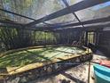 Enclosed pool with artificial turf and a rock border set among lush greenery at 32348 Marchmont Cir, Dade City, FL 33523