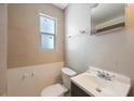 Bathroom with white toilet, dark vanity with sink, and small window at 513 88Th N Ave, St Petersburg, FL 33702