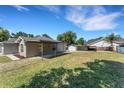 Spacious backyard featuring lush green grass and various storage and car port structures on a sunny day at 7222 N Amos Ave, Tampa, FL 33614