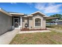 Home's entrance featuring a decorative security door, a white window, and a convenient carport on a well-manicured lot at 7222 N Amos Ave, Tampa, FL 33614