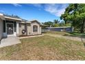 Side view of the home, showcasing the well-maintained lawn, carport and utility shed on a sunny day at 7222 N Amos Ave, Tampa, FL 33614