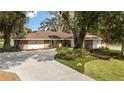 A charming single story home with brick and siding, mature trees, manicured landscaping, and a long concrete driveway at 9542 Wallien Dr, Brooksville, FL 34601