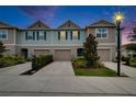 Charming townhome featuring a front-entry garage, landscaped yard, and a well-manicured lawn under the evening sky at 10907 Golden Acorn Ave, Tampa, FL 33610