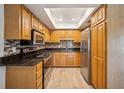 Well-equipped kitchen with stainless steel appliances, dark countertops, and wood cabinets, ready for cooking at 15202 Morning Dr, Lutz, FL 33559