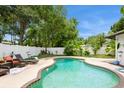 Private backyard oasis featuring a kidney-shaped pool, lounge chairs, and lush landscaping behind a white fence at 15801 Cottontail Pl, Tampa, FL 33624