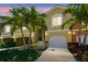 Inviting townhouse showcasing a manicured front yard, palm trees, a two-car garage, and a charming facade at 17 Franklin S Ct # C, St Petersburg, FL 33711