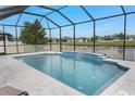 Inviting screened-in pool area with tiled deck, a decorative waterfall feature and view of the neighborhood pond at 18827 Henequen Lane, Spring Hill, FL 34610