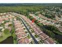 Bird's-eye view showcases the community layout with uniform red-tiled roofs, lush green spaces, and a serene waterway running through it at 3875 Darston St, Palm Harbor, FL 34685